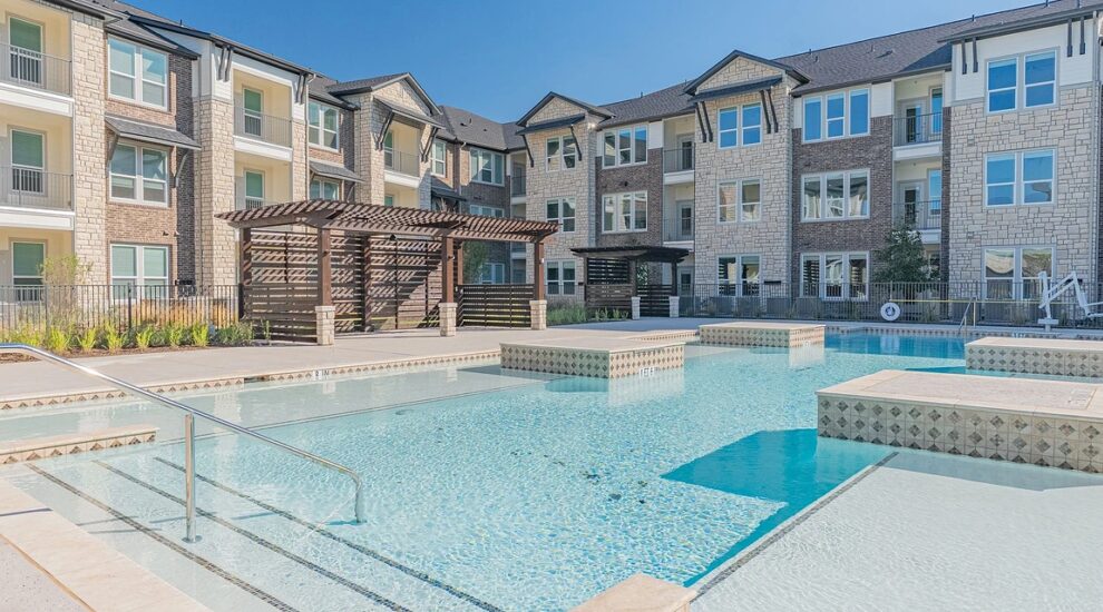 Swimming pool with seating and view of apartment building